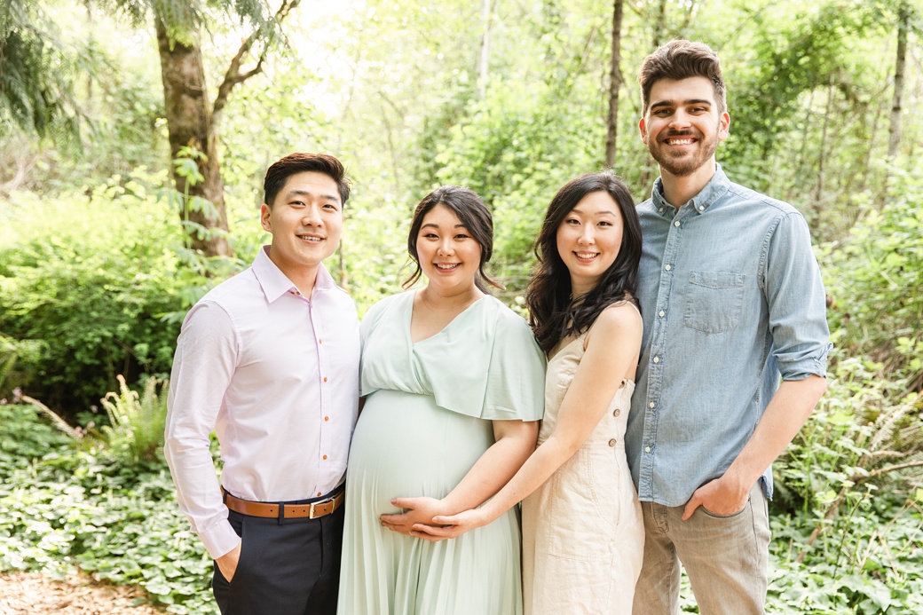 Expecting mother with husband, sister, and brother in law smiling together