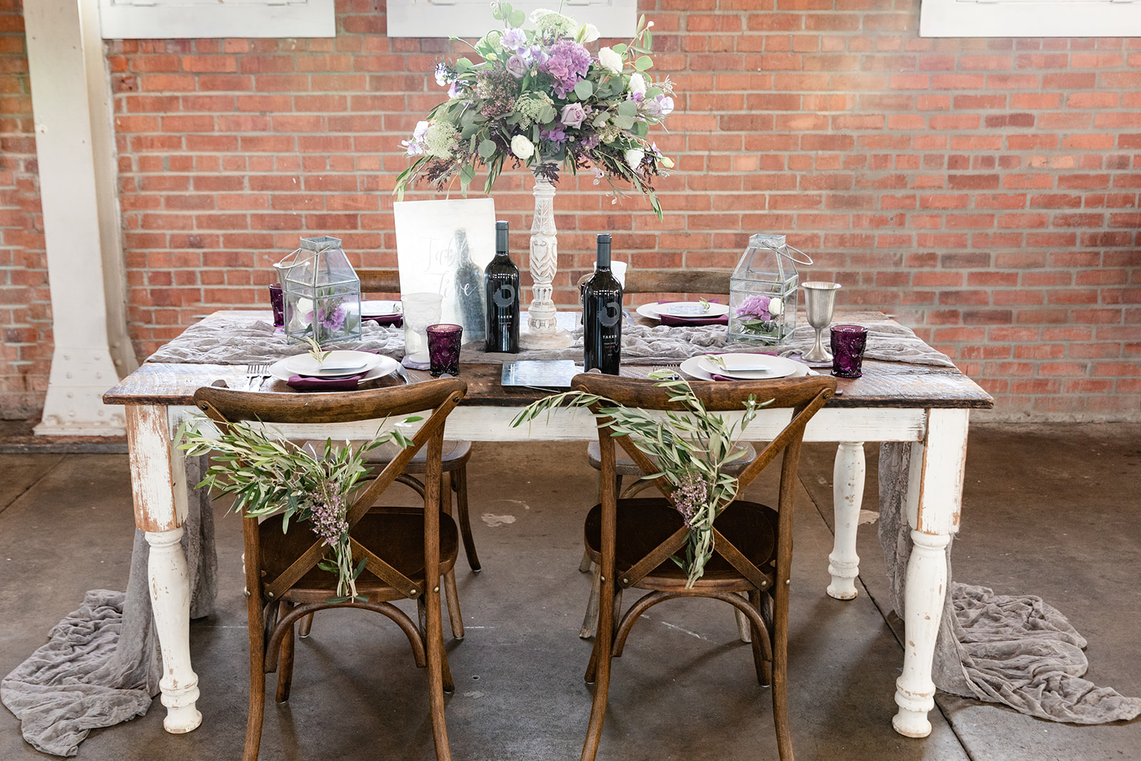 wedding reception table; wine bottles, floral centerpiece, lanterns
