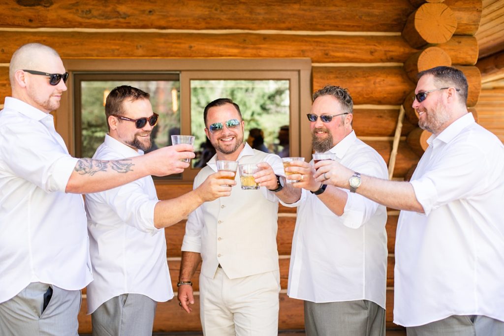 Groom and groomsmen clinking alcohol glasses at wedding in Leavenworth, WA
