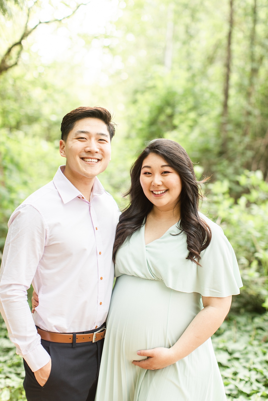 Maternity photo of dad and mom to be smiling at photographer
