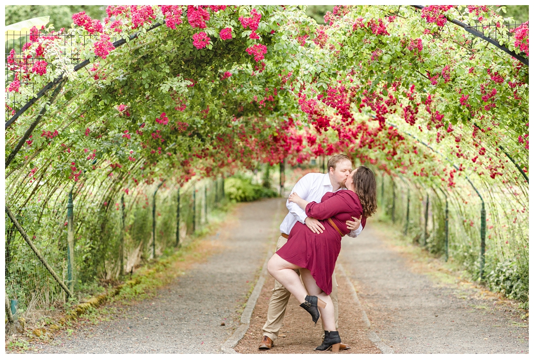 couple dip kissing in front of rose arch